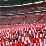 **A packed stadium of Spartak Moscow fans**: Depict a vibrant scene inside Spartak Stadium, filled with passionate fans wearing red and white scarves, cheering and waving flags. Capture the intense energy and excitement of a match day.