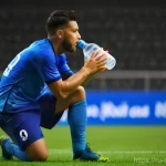 축구 경기 중 수분 섭취 요령 - A male football player in his mid-20s, actively engaged in a match, takes a quick, vital drink from ...